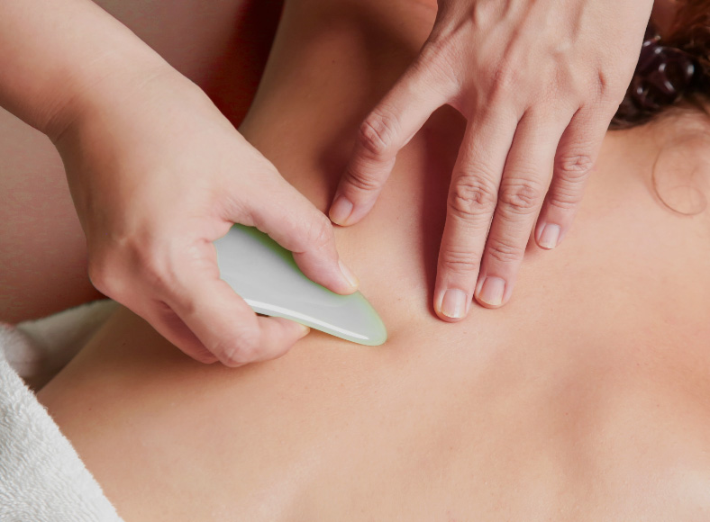 Gua Sha-Anwendung mit Schaber auf dem Rücken – traditionelle Ausstreichtechnik der TCM